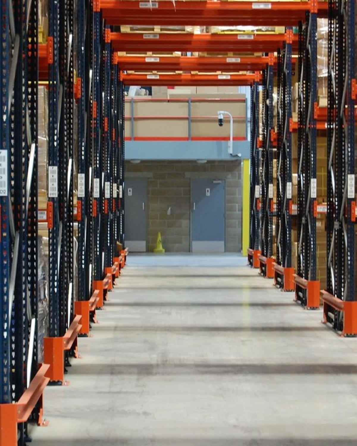 A narrow aisle between tall pallet racks in a bonded warehouse