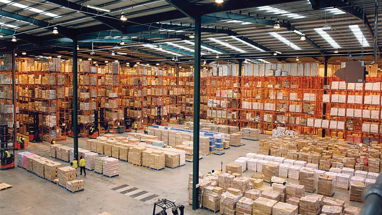A cross-dock warehouse with pallet racking on both sides and freight staged on the floor